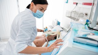 Foto genérica de una mujer atendiendo a un paciente en un hospital.