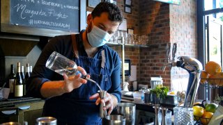 In this July 24, 2020, file photo, a bartender wearing a protective mask makes a drink at a restaurant in Chicago, Illinois.