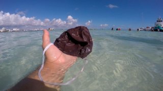 Una mano sostiene un cubrebocas que sacaron del mar de Cancún