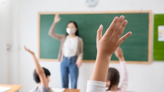 students in class raise hands