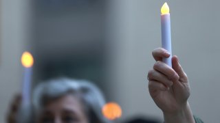 People hold up electric candles during a prayer vigil for victims of the coronavirus (COVID-19) pandemic.