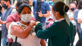 Una enfermera aplica una vacuna a una mujer migrante en Tijuana
