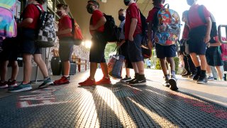 Wearing masks to prevent the spread of COVID-19, elementary school students line up to enter school for the first day of classes in Richardson, Texas, Tuesday, Aug. 17, 2021. Despite Texas Gov Greg Abbott's executive order banning mask mandates by local officials, the Richardson Independent School District and many others across the state are requiring masks for students.