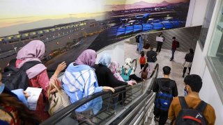 Un grupo de ciudadanos afganos bajan escaleras en el aeropuerto de Ciudad de México, país que les dio refugio