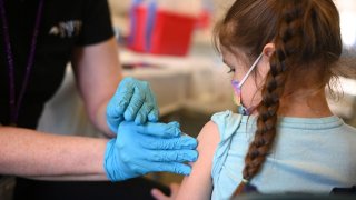 A nurse administers a pediatric dose of the Covid-19 vaccine to a girl at a L.A. Care Health Plan vaccination clinic at Los Angeles Mission College