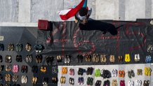 A demonstrator holds a Puerto Rican flag near empty pairs of shoes outside the Capitol building in this aerial photograph taken during a protest against the government's reporting of the death toll from Hurricane Maria in San Juan, Puerto Rico, on Friday, June 1, 2018. Hurricane Maria probably killed about 5,000 people in Puerto Rico last year even though the official count remains at just 64, according to a Harvard University study released Tuesday. Photographer: Xavier Garcia/Bloomberg via Getty Images