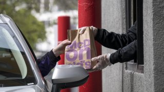 Un empleado entrega un pedido a un cliente a través de una ventanilla de autoservicio en un restaurante McDonald's en Oakland, California, el 9 de abril de 2020.