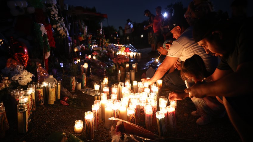 SAN ANTONIO, TEXAS – 29 DE JUNIO: La gente visita y conmemora a las víctimas durante las horas nocturnas del 29 de junio de 2022 mientras encienden velas y dejan flores y botellas de agua en un monumento improvisado donde 53 migrantes fueron encontrados muertos en un tractor-remolque en San Antonio, Texas, Estados Unidos. (Foto de Tayfun Coskun/Anadolu Agency vía Getty Images)