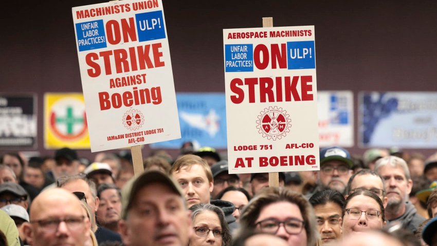 People hold sings during a strike rally for the International Association of Machinists and Aerospace Workers (IAM) at the Seattle Union Hall in Seattle, Washington, on October 15, 2024.