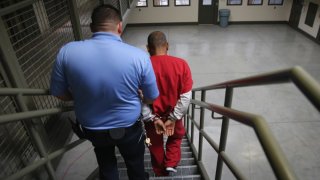 Un guardia con un inmigrante esposado en el Centro de Detención de Adelanto en California.