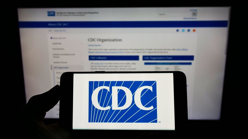 Stuttgart, Germany – 01-15-2022: Person holding cellphone with logo of US Centers for Disease Control and Prevention (CDC) on screen in front of webpage. Focus on phone display. Unmodified photo.