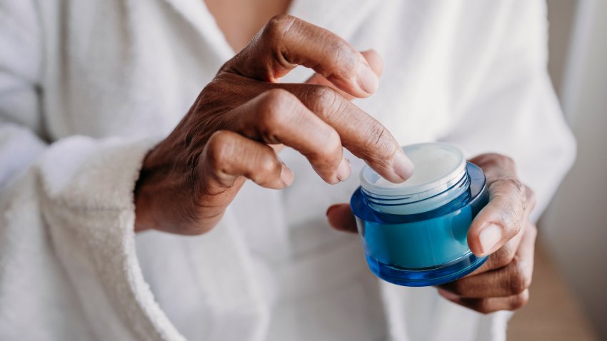 Hands of woman with moisturizer in bathroom at home