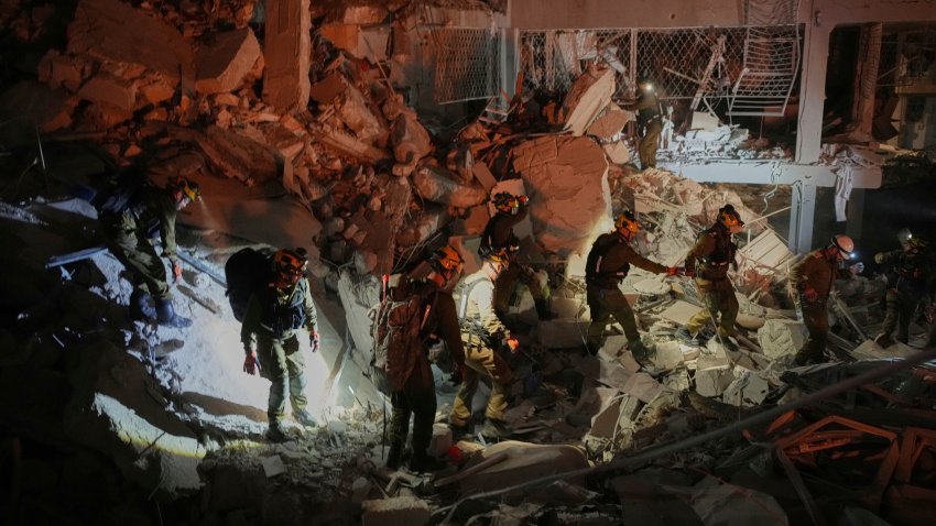 Israeli security forces inspect a destroyed building that was hit by a missile fired from Iran, near Tel Aviv, Israel, early Sunday, June 15, 2025.
