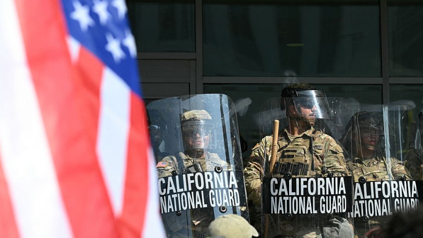 A demonstrator holds an upside down US flag as they face California National Guard members standing guard outside the Federal Building during a protest in response to federal immigration operations in Los Angeles, on June 9, 2025. US President Donald Trump on June 9 ordered active-duty Marines into Los Angeles, vowing those protesting immigration arrests would be “hit harder” than ever. Protests in Los Angeles, home to a large Latino population, broke out on June 6, triggered by immigration raids that resulted in dozens of arrests of what authorities say are illegal migrants and gang members. (Photo by RONALDO SCHEMIDT / AFP) (Photo by RONALDO SCHEMIDT/AFP via Getty Images)
