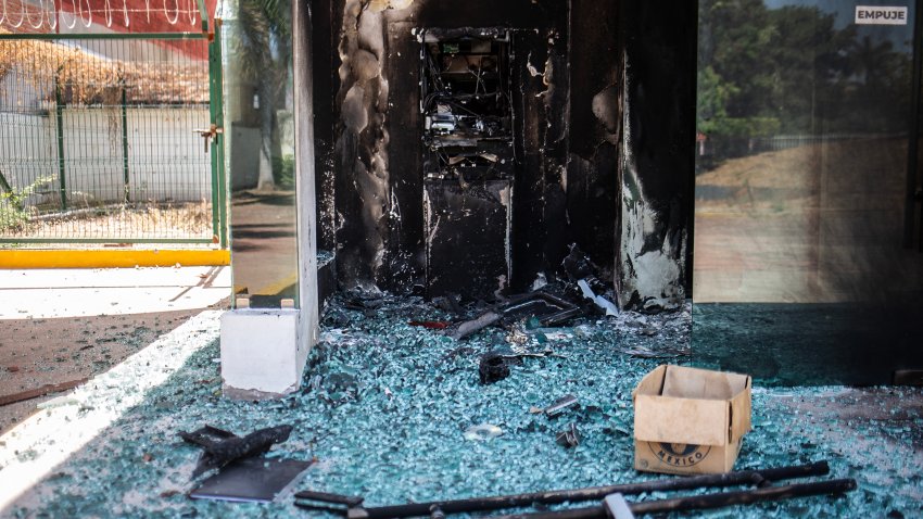 Un cajero automático incendiado del Banco del Bienestar, propiedad del estado, se muestra tras una ola de violencia en la ciudad de Aguililla, cuna del narcotraficante Nemesio Oseguera, líder del Cártel Jalisco Nueva Generación (CJNG) en Tierra Caliente, México, el 24 de febrero de 2026. La presidenta mexicana, Claudia Sheinbaum, desestimó el 24 de febrero los riesgos para los aficionados que visitan Guadalajara, una de las sedes del Mundial de 2026, después de que un motín de un cártel de la droga causara temor en la ciudad y gran parte del país el 22 de febrero. (Foto de Enrique Castro / AFP vía Getty Images)