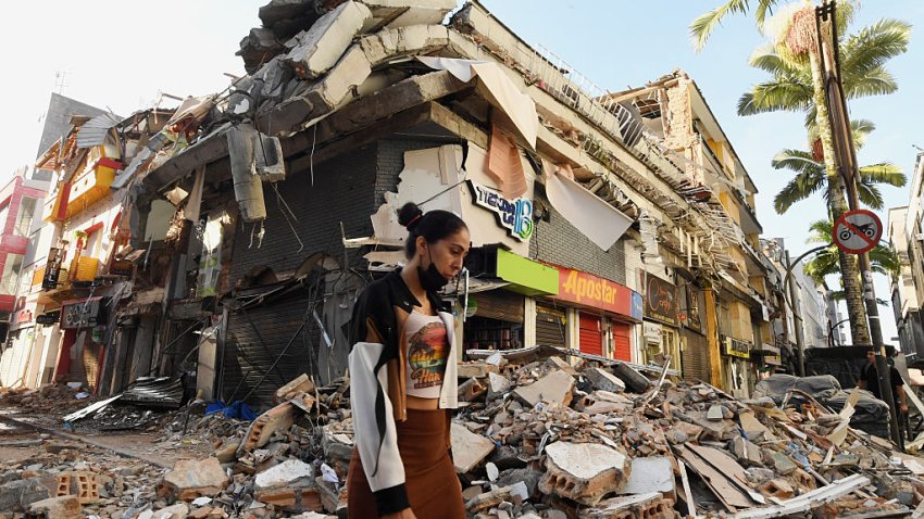 A woman walks past the rubble of a collapsed building after an earthquake in Pereira, Colombia on August 11, 2026. Colombian volunteers and rescuers cleared rubble with their bare hands to search for survivors early on August 11 after the country’s strongest earthquake in a decade killed at least 169 people and smashed dozens of buildings. (Photo by Jaime SALDARRIAGA / AFP via Getty Images)